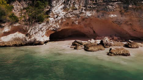 aerial pullback reveals picturesque caribbean coastline, sea caves on beach