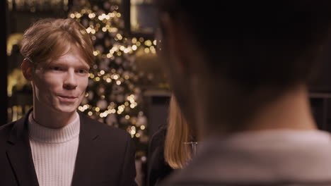 Close-Up-View-Of-Red-Haired-Man-Wearing-Stylish-Clothes-While-Talking-And-Holding-Champagne-Glasses-At-New-Year's-Party