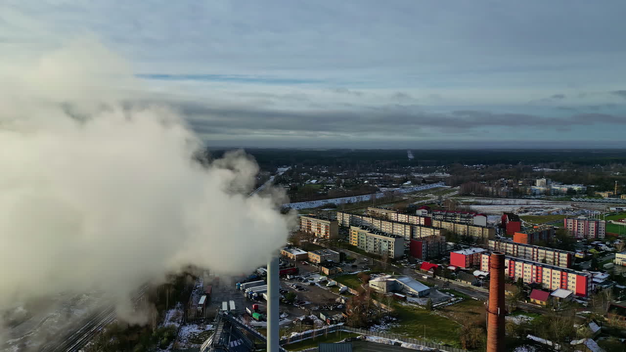 vista aerea che passa un camino di fabbrica fumante con condomini sullo sfondo