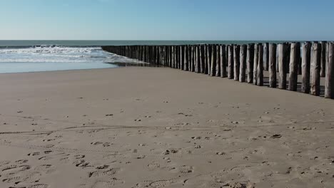 dolly shot of a double wooden breakwater on the beach, blue sky, the sea and no people