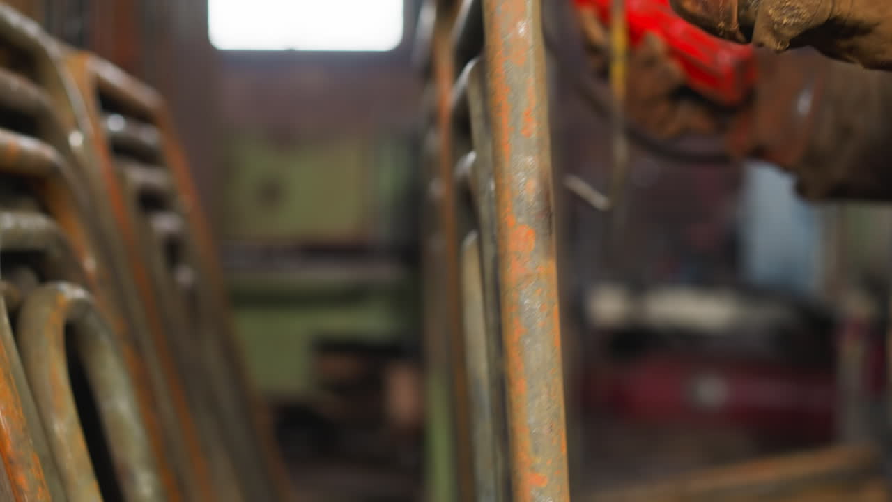 Worker in gloves takes metal frame out of hook in storage