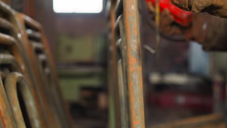worker in gloves takes metal frame out of hook in storage
