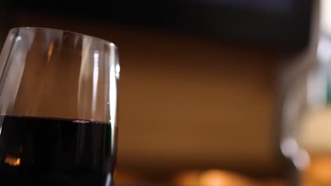 a focused shot of a wine glass with a softly blurred background, highlighting the beverage's rich color.