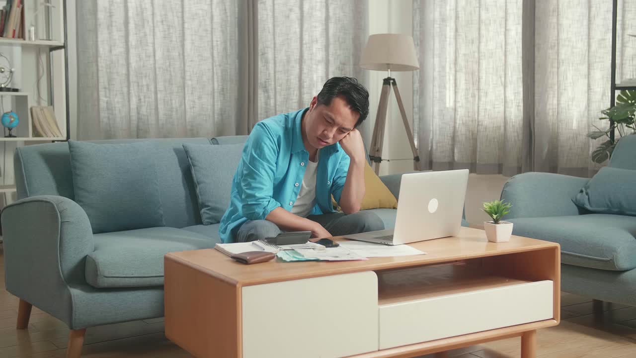 소파에 앉아 슬프고 있는 노트북을 가진 아시아인