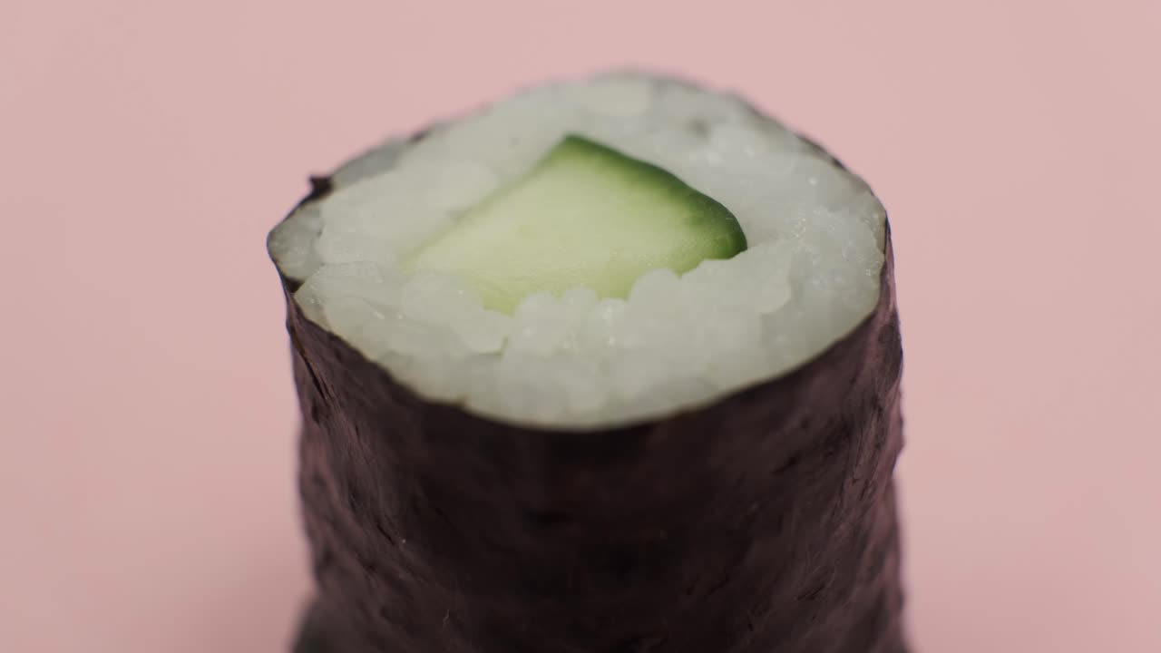 un rollo de sushi girando sobre un fondo rosado