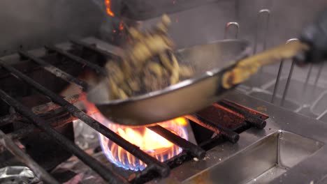 professional chef mixing and frying meat and mushroom on metal pan, close up