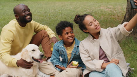 happy black family taking selfie with dog on picnic