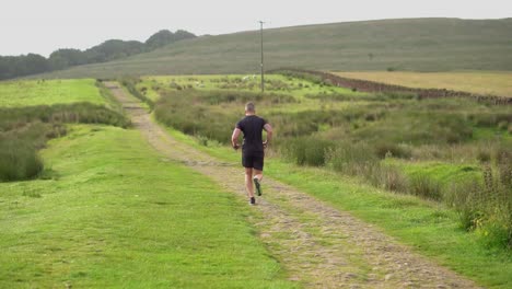 an athletic man running along a countryside path