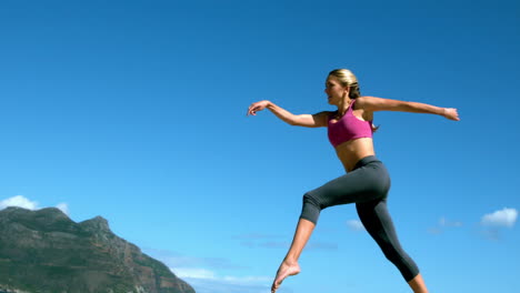 rubia en forma corriendo y saltando en la playa