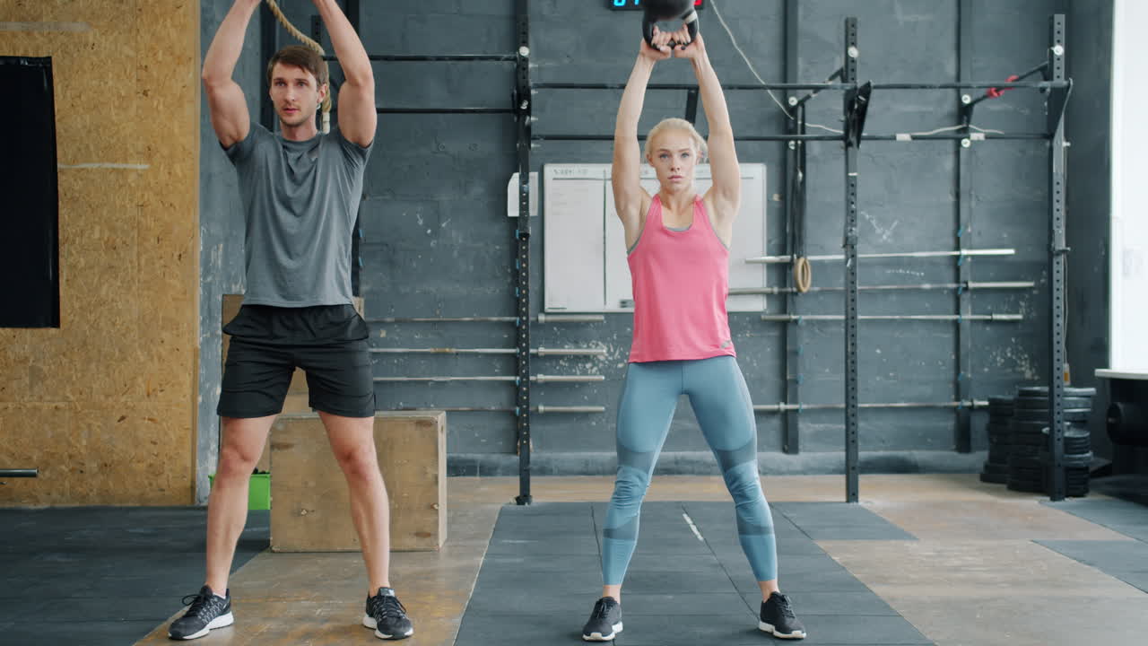 Couple working out with kettlebells in a gym