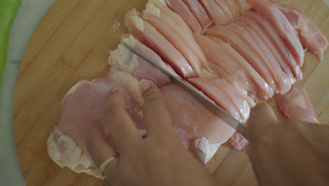 cutting chicken breast on a cutting board