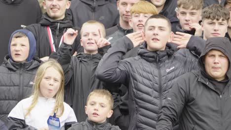 teenage soccer supporters gesturing, stadium rivals, scottish football