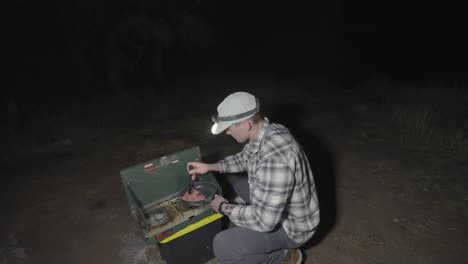 man cooking dinner on a camping stove