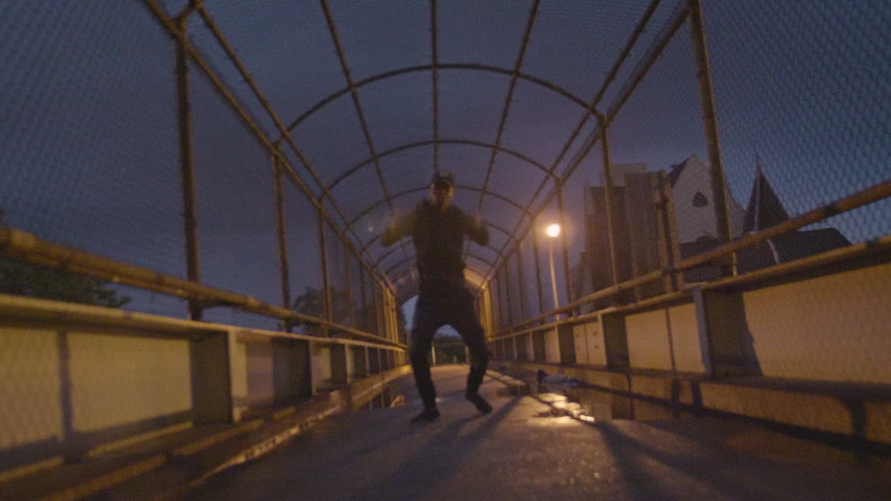 hombre afroamericano bailando en un puente durante una noche lluviosa