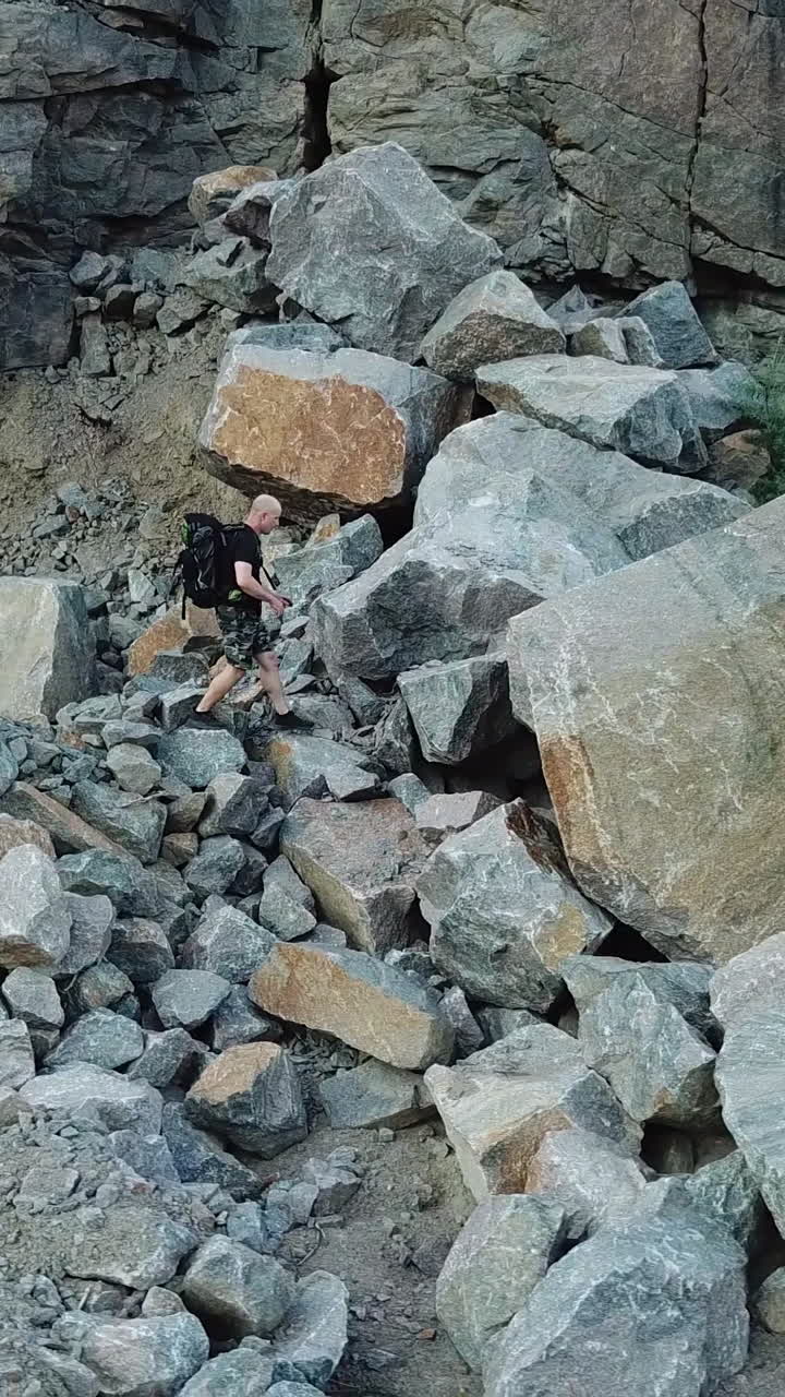 Man Walking along Giant Rocky Mountain Wall. Travel concept. Aerial view Vertical video