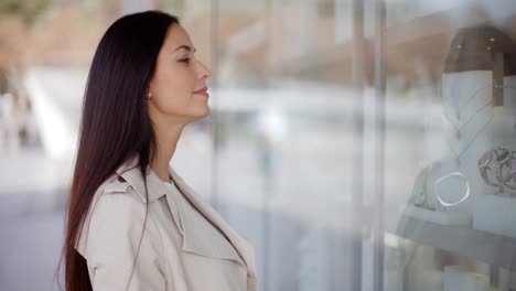 Thoughtful-young-woman-eyeing-shop-merchandise