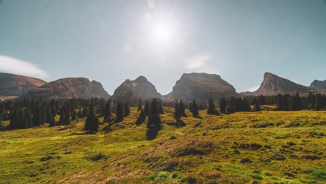 this still timelapse captures the churfirsten peaks in toggenburg, st. gallen, switzerland. the sun shines over rolling green meadows and dark fir trees, casting long shadows against rugged cliffs.