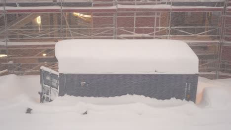 contenedor con puerta abierta en el sitio de construcción cubierto con enormes cantidades de nieve - edificio en construcción con andamios en el fondo - clip estático en clima nevado myrkdalen noruega