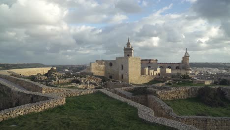 Ruinas-De-La-Fortaleza-De-Cittadella-Y-Casas-Llenas-De-Vegetación-En-Una-Soleada-Tarde-Dorada