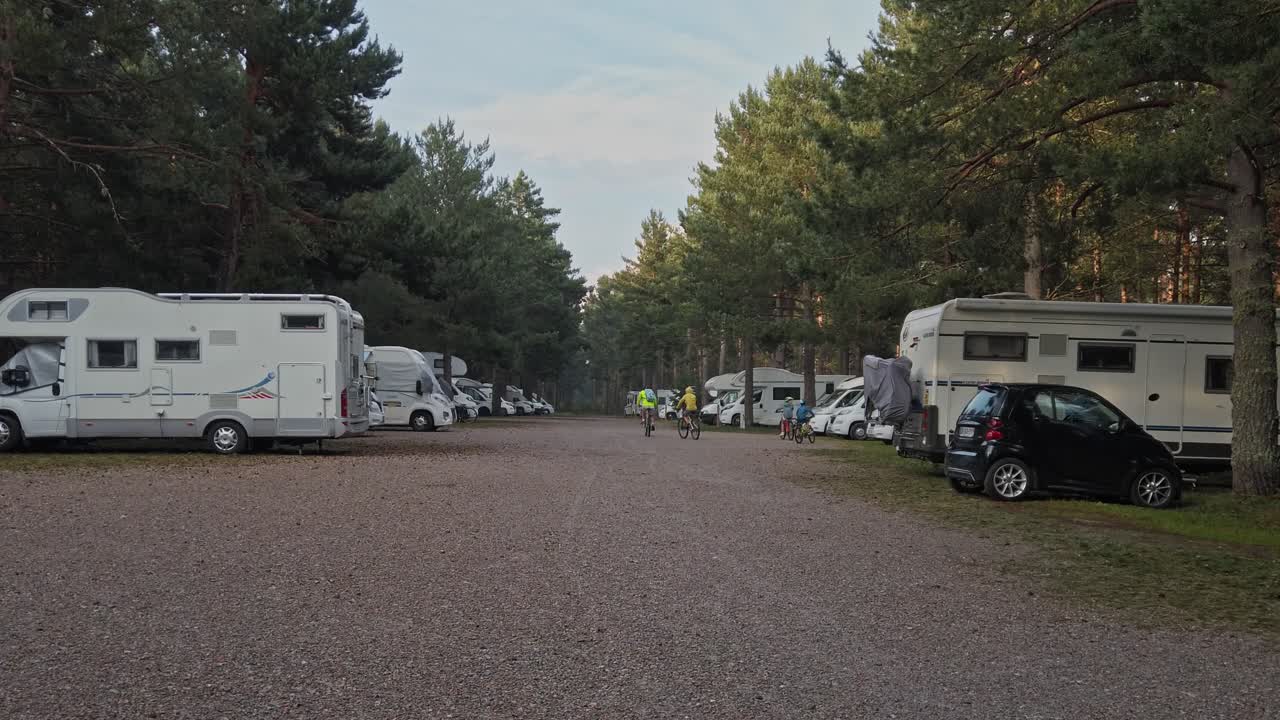 Family of four arriving on bicycles to campsite after long day, family cycling holiday