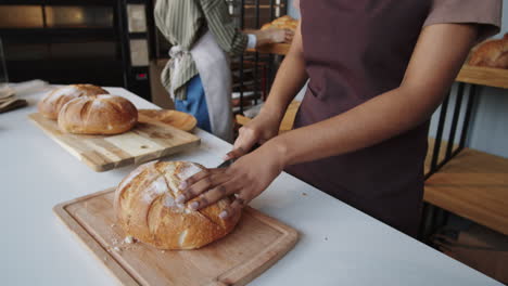 black woman cutting fresh bread in bakery