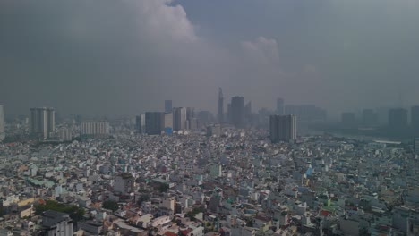 aerial view of ho chi minh city skyline with high density urban area in foreground with dramatic morning sky. flying backwards high over rooftops