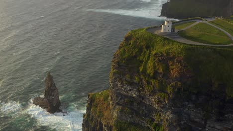 Angled-aerial-of-O'Brien's-Tower-and-sea-stack-at-Cliffs-of-Moher-during-golden-hour