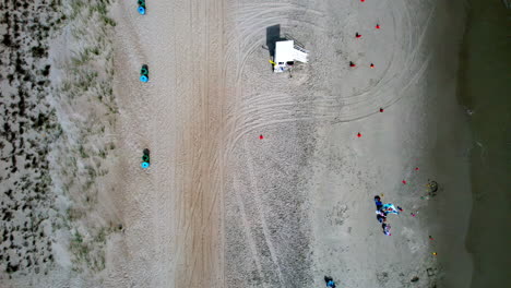 Downward-angle-drone-shot-of-shoreline-with-just-a-few-people-on-the-sand