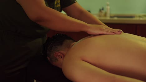 latino mexicano hombre modelo tipo recive una espalda relajante sexy terapia de masaje lento en el centro de bienestar spa resort luz vela oscuro de humor cámara lenta