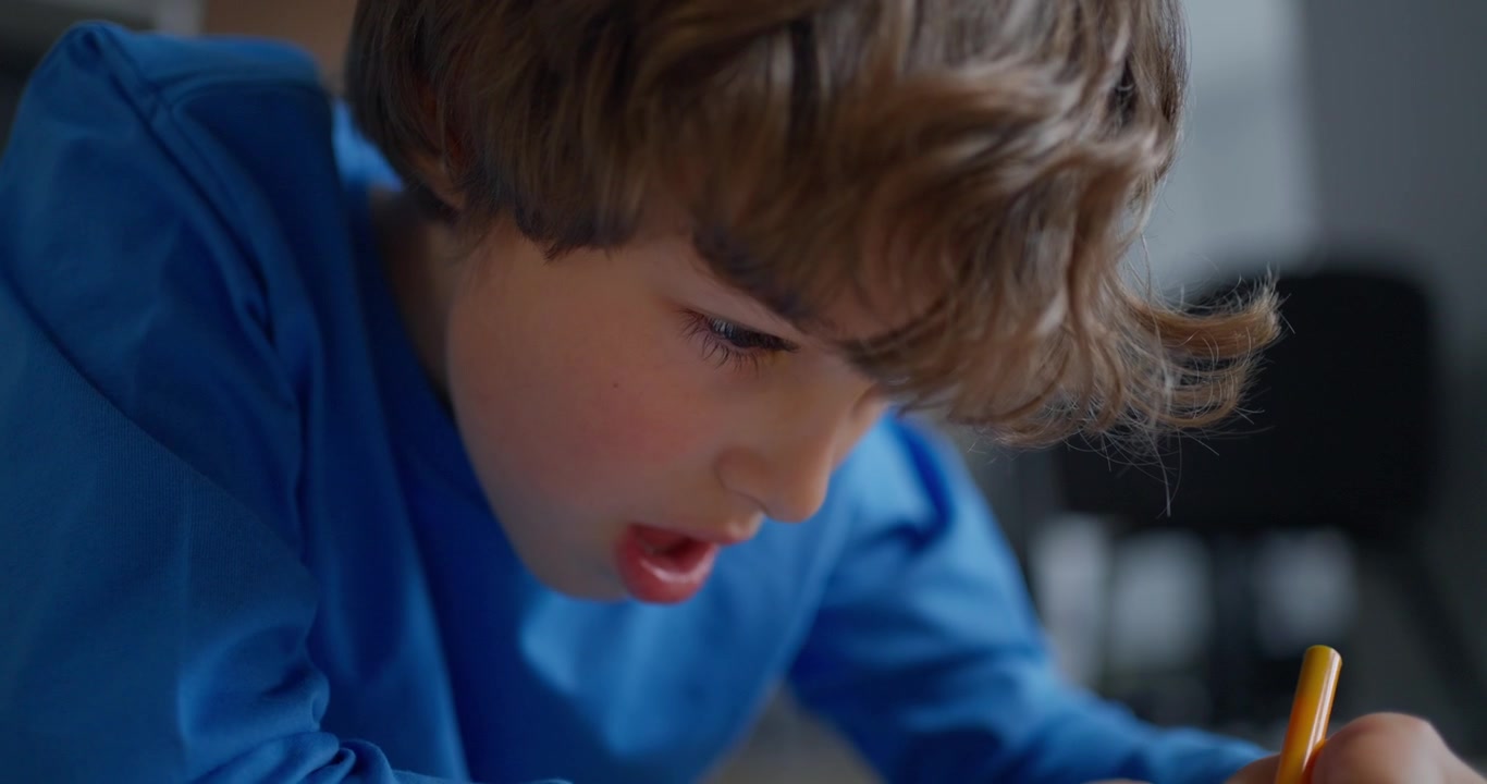 Giovane ragazzo concentrato mentre disegna con una matita