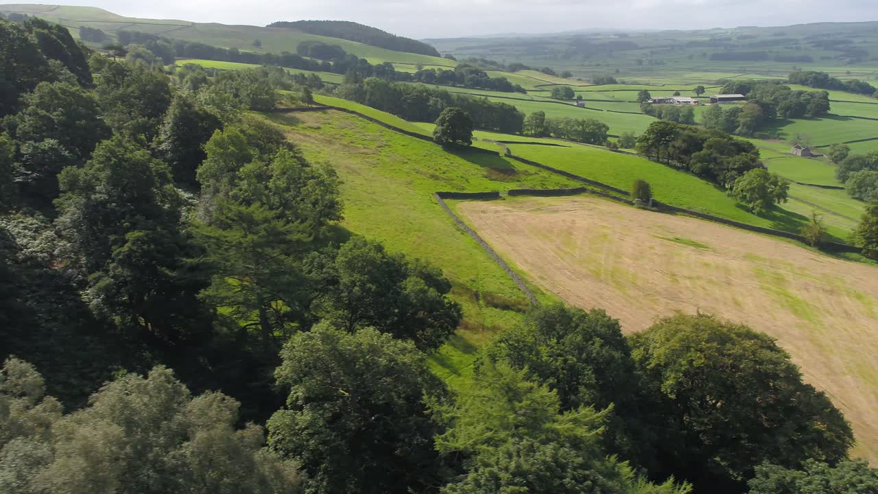 imágenes de aviones no tripulados moviéndose lentamente y de lado sobre un valle poco profundo cerca de la aldea rural de settle, north yorkshire, reino unido