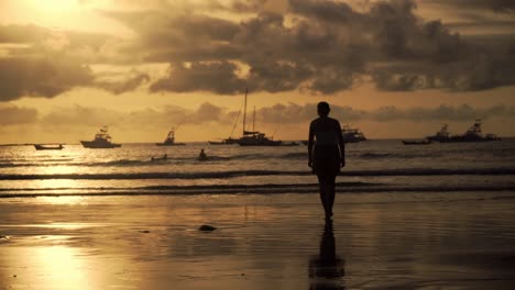 woman silhouette walking at a beach in tamarindo in costa rica with boats in the background