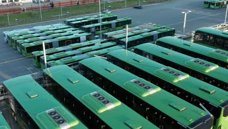 aligned green electric buses in bus park, drone aerial view