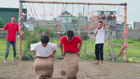group of young indonesian men participating in traditional sack race, celebrating national holiday with laughter and friendly competition