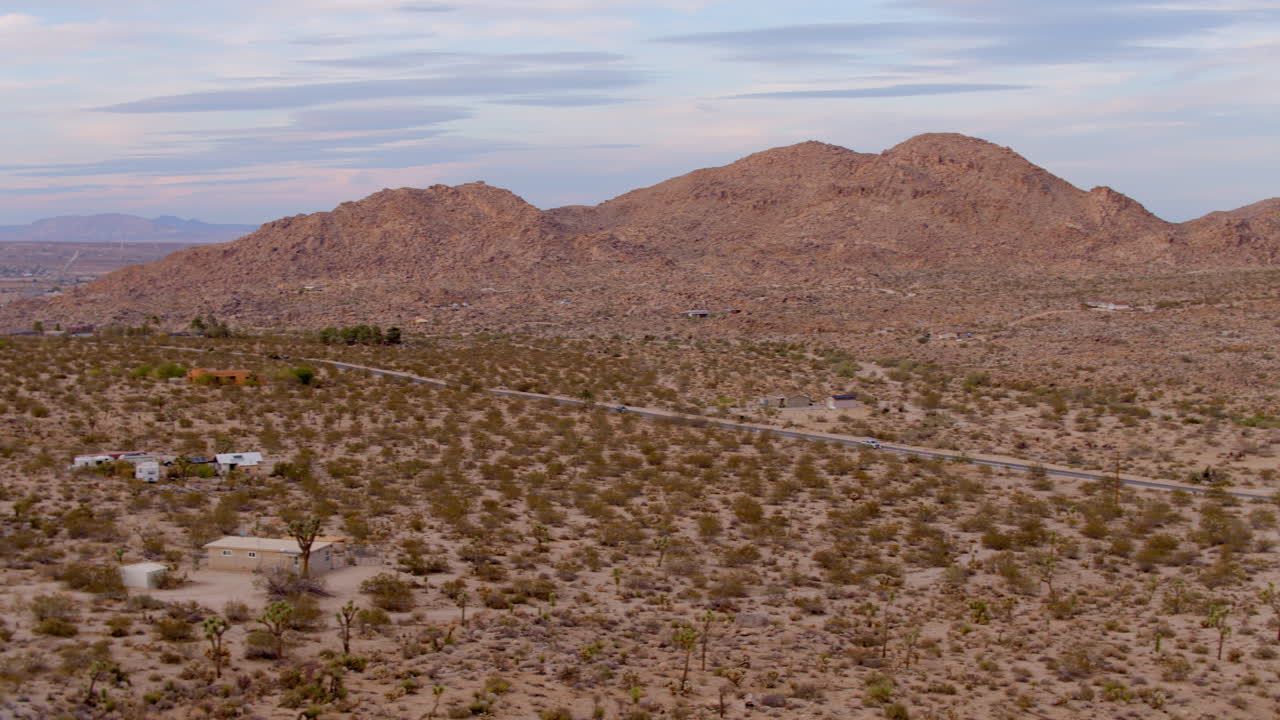 Vista aerea del deserto a Joshua Tree, California, con una panoramica a destra che segue un camion bianco mentre attraversa il paesaggio.