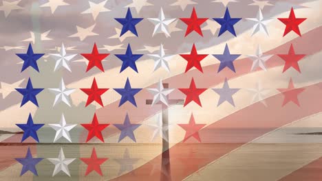 animation of stars in usa flag colours over flag of usa and cross over seascape at sunset