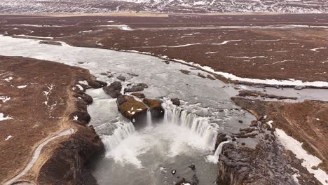 goðafoss waterfall in iceland surrounded by snow-covered landscape