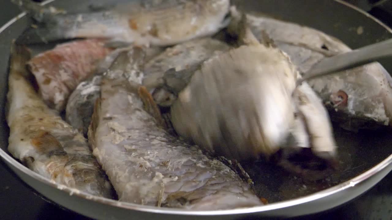 그 여자는 가까이서 볼 수 있는 팬에 생선을 튀기고 뒤집는다