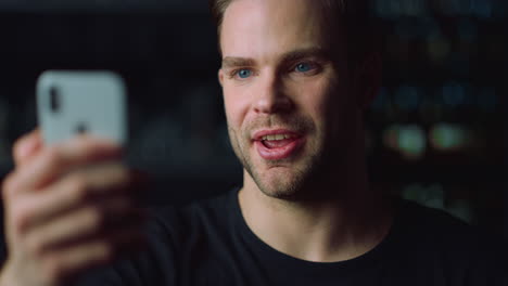 portrait of handsome young man making video call from smartphone indoors.