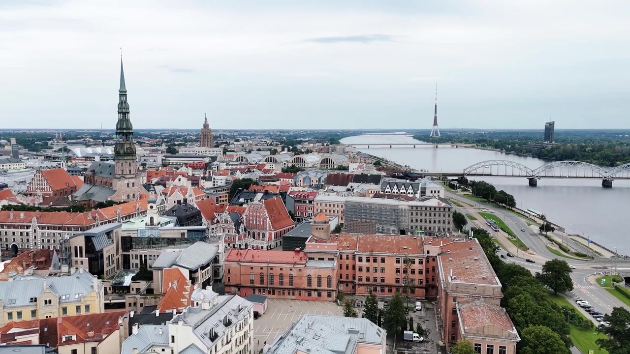 Il centro storico di Riga con la Chiesa di San Pietro si erge sopra i tetti rossi mentre il fiume Daugava, i ponti e la Torre della TV di Riga si estendono in lontananza