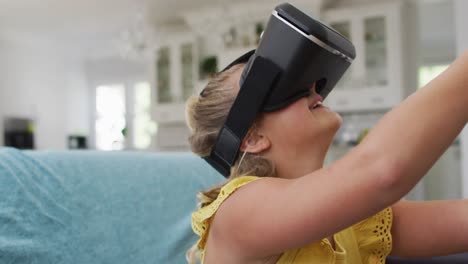 Glückliches-Kaukasisches-Mädchen-Zu-Hause,-Das-Auf-Der-Couch-Sitzt,-Ein-VR-Headset-Trägt-Und-Lächelt