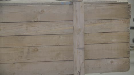 una carretilla elevadora que transporta una gran caja de madera se mueve hacia la cámara en una nave industrial