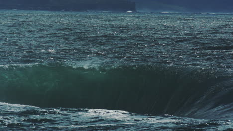 crashing wave in deep water expels white mist and churns into sea foam, dark ocean backdrop