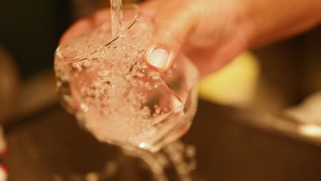 una mano limpia un vaso con agua corriente
