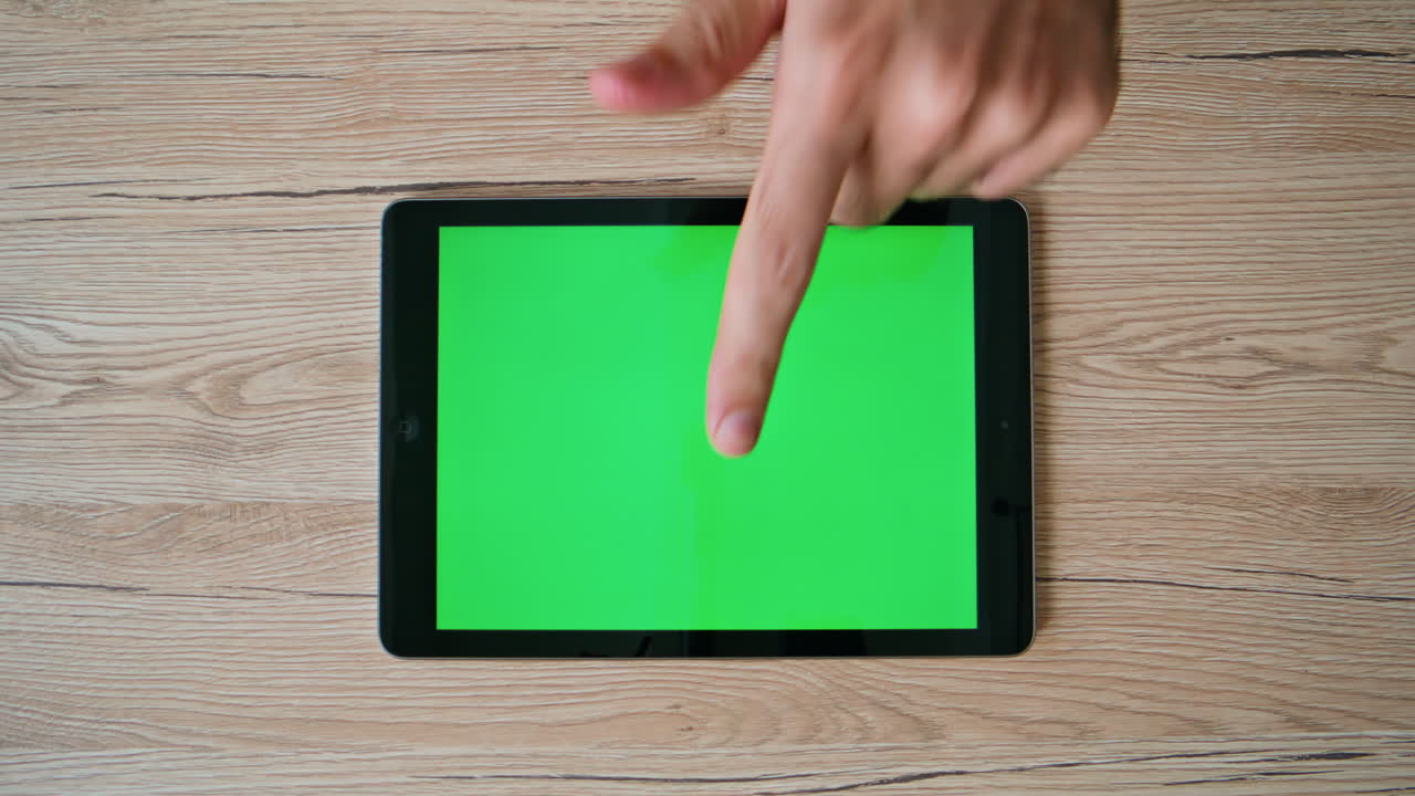 Tablet user swiping green screen touchscreen browsing website at home closeup