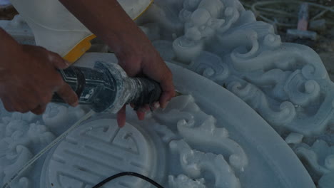 Hands-of-sculptor-carving-and-detailing-white-marble-stone-using-hand-tool,-Da-Nang-city,-Vietnam