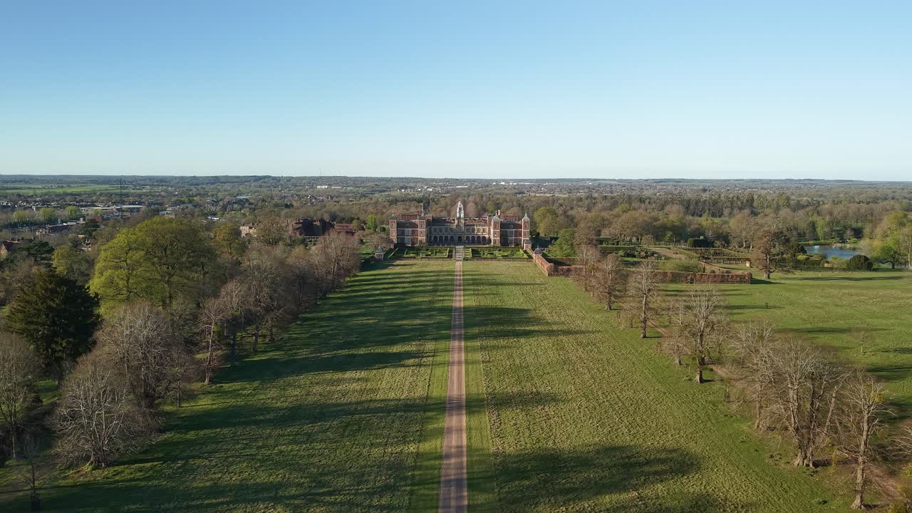 Aerial view descending to Hatfield house vast wealthy countryside mansion with manicured gardens