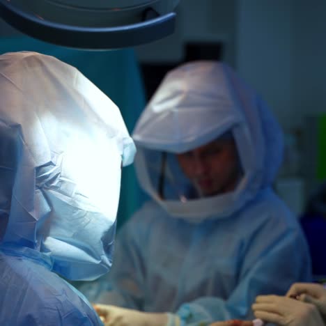 surgical procedure in hospital. group of doctors in a safety dressing gowns perform operation in the operating room. surgeons use medical tools.