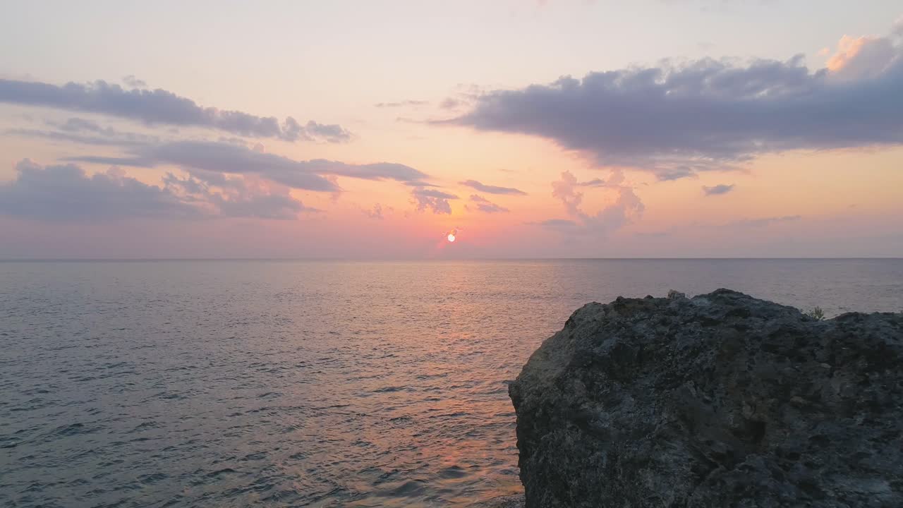 바다의 바위 형상 위에서 조용한 해가 지는 것