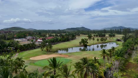 aerial view of a lush golf course in phuket, thailand, showcasing vibrant greens and serene water features under a clear sky